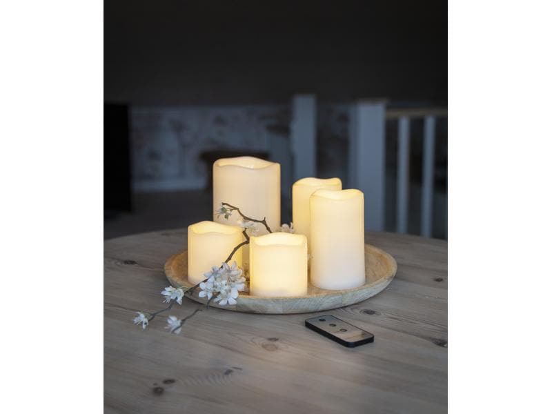 LED-Kerzen auf rundem Holztablett mit Winterzweig und Fernbedienung