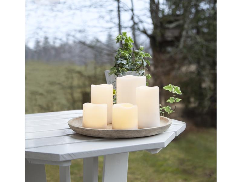LED-Kerzen Pillar Paul auf einem Holztablett auf einem Gartentisch im Freien