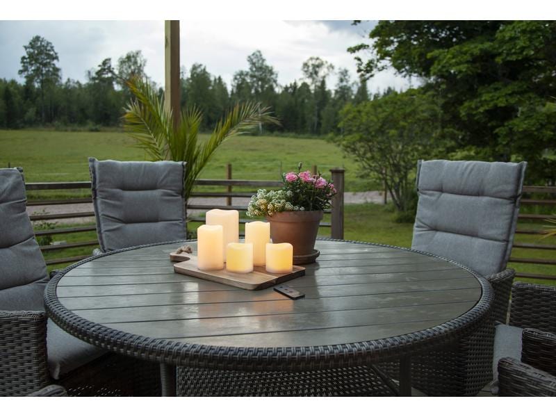 LED-Kerzen auf einem Holztablett als Tischdeko auf der Terrasse zwischen Gartenstühlen